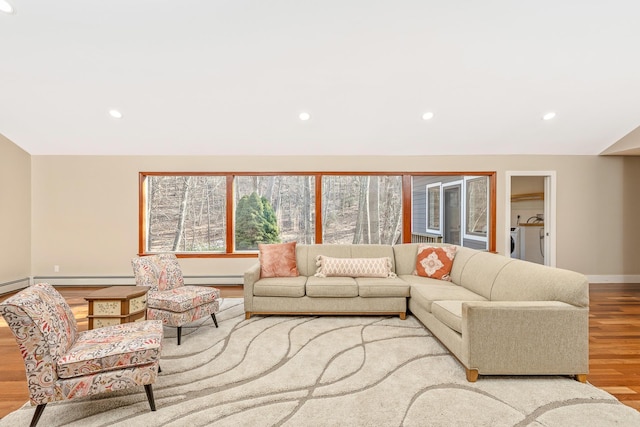 living area with lofted ceiling, recessed lighting, light wood-style flooring, a baseboard heating unit, and washer and dryer