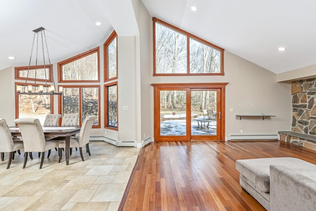 dining space with light wood-style flooring, an inviting chandelier, baseboard heating, high vaulted ceiling, and recessed lighting