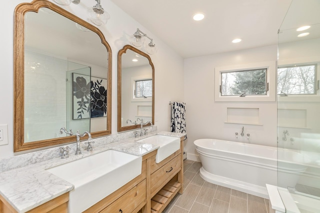 full bath with recessed lighting, a soaking tub, a sink, and double vanity