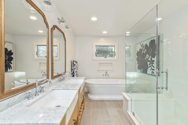 bathroom featuring a freestanding tub, recessed lighting, a sink, double vanity, and a stall shower