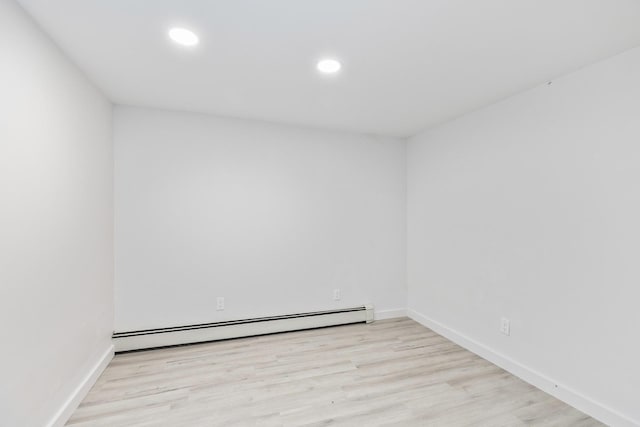 spare room with a baseboard radiator, baseboards, light wood finished floors, and recessed lighting