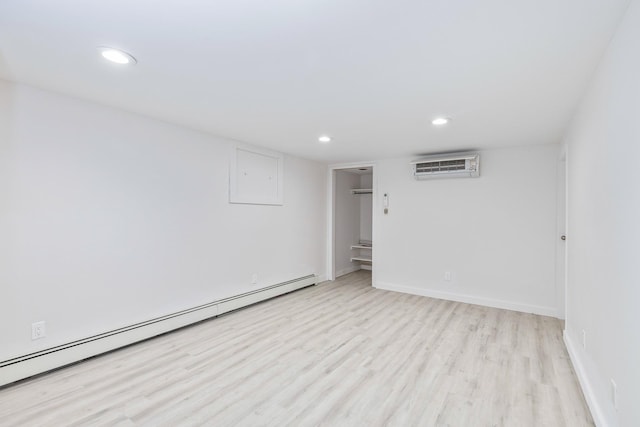 spare room featuring recessed lighting, baseboard heating, light wood-style floors, an AC wall unit, and baseboards