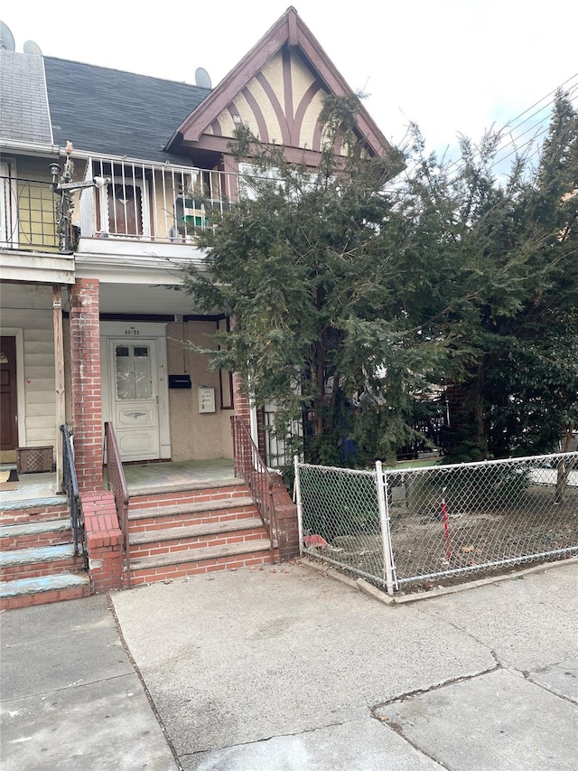 exterior space with covered porch, a fenced front yard, and a balcony