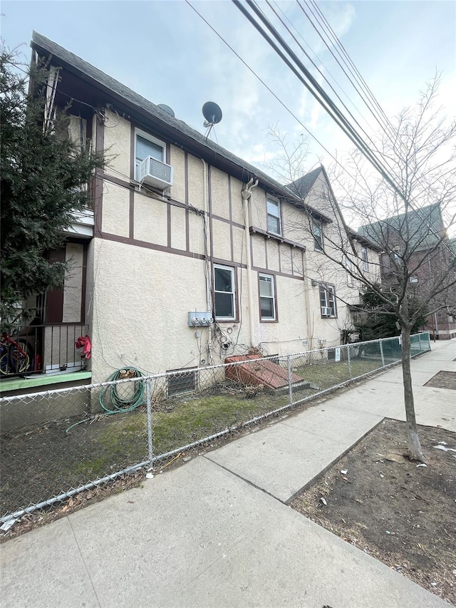 view of property exterior featuring cooling unit, fence, and stucco siding