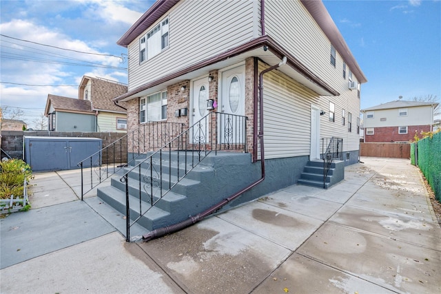 view of front of property with brick siding, fence, and a patio