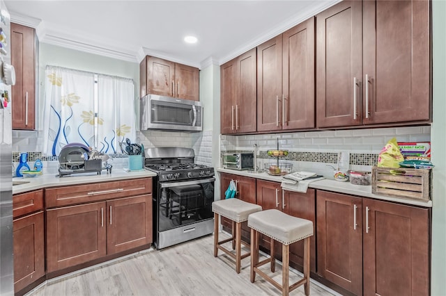 kitchen with a toaster, stainless steel appliances, light countertops, light wood finished floors, and tasteful backsplash