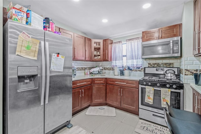 kitchen with light countertops, appliances with stainless steel finishes, glass insert cabinets, and tasteful backsplash