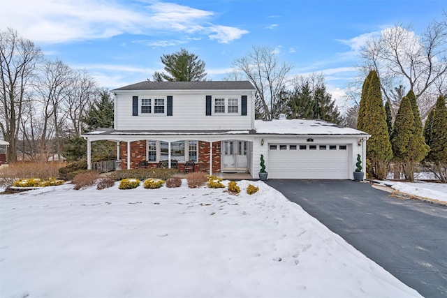 traditional home with a garage, driveway, brick siding, and a porch