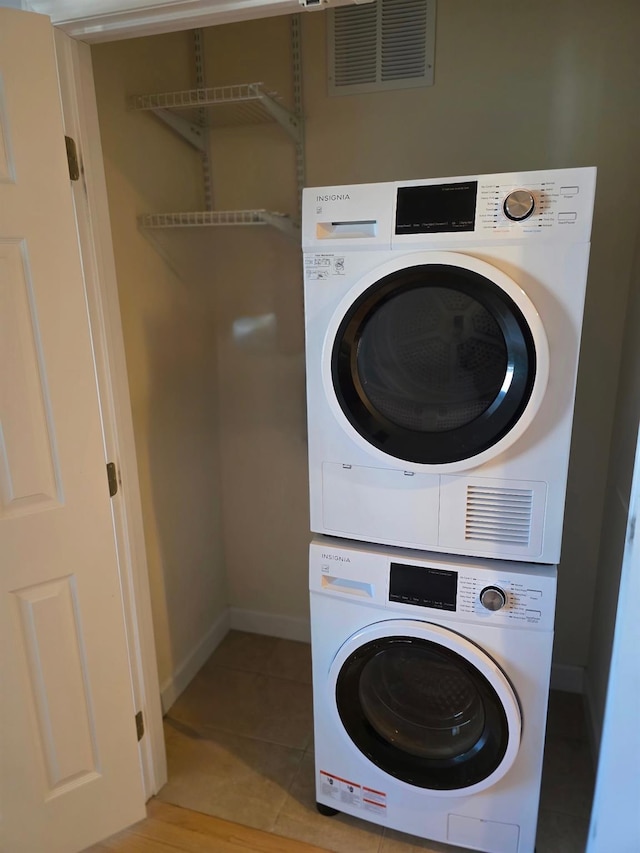 clothes washing area featuring laundry area, light tile patterned floors, baseboards, visible vents, and stacked washer / dryer