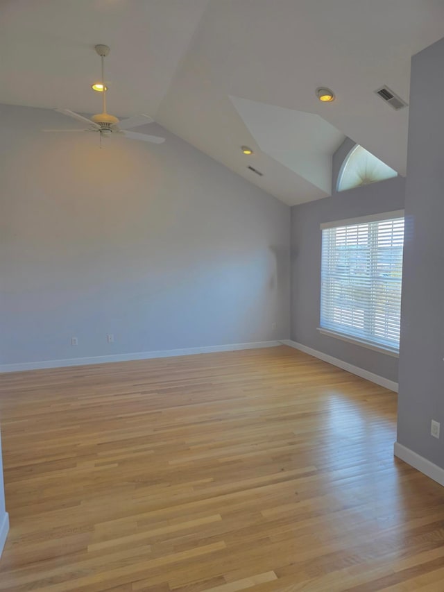 spare room featuring light wood finished floors, baseboards, visible vents, ceiling fan, and vaulted ceiling