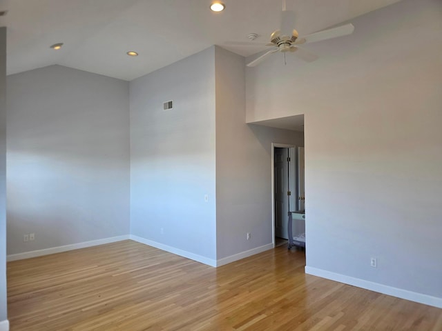 unfurnished room with ceiling fan, vaulted ceiling, light wood-style flooring, and baseboards