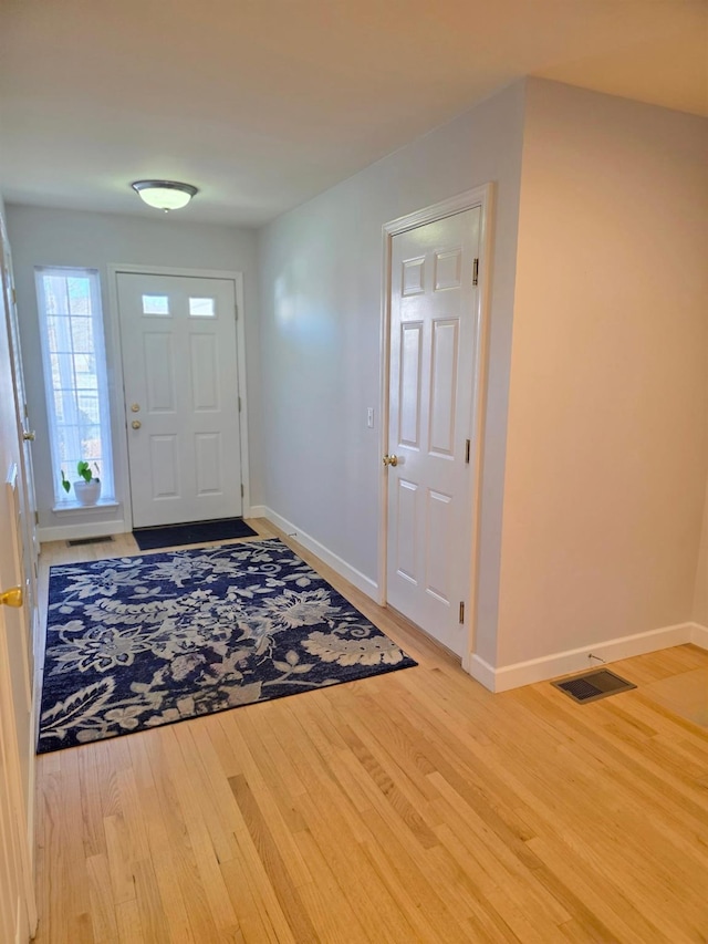 foyer with light wood-type flooring, baseboards, and visible vents