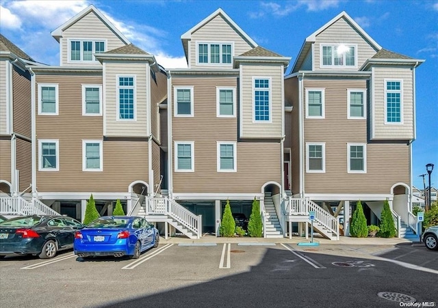 view of property featuring uncovered parking and stairway