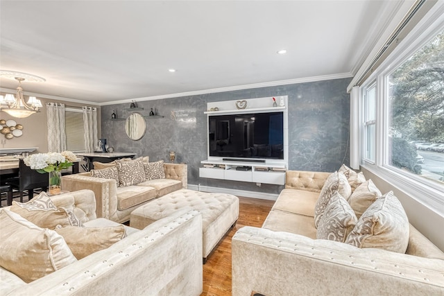 living room with a chandelier, wallpapered walls, crown molding, and wood finished floors