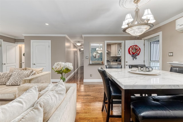 dining space with baseboards, ornamental molding, a notable chandelier, and wood finished floors