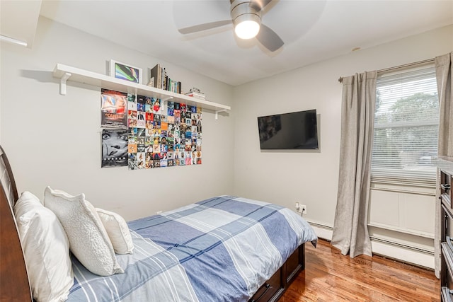 bedroom featuring a ceiling fan, baseboard heating, and wood finished floors