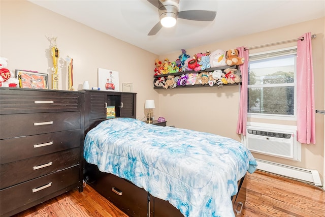 bedroom featuring light wood-type flooring, a wall mounted AC, a baseboard radiator, and a ceiling fan