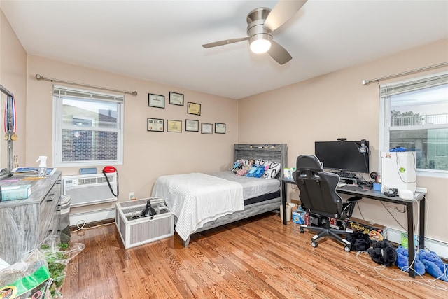 bedroom with a ceiling fan, a wall unit AC, and light wood finished floors