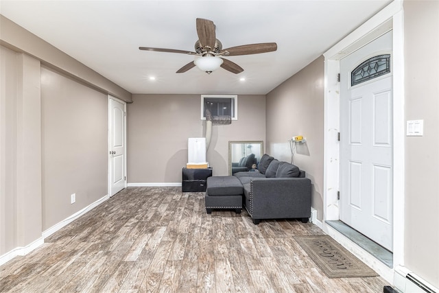 living area with recessed lighting, a baseboard heating unit, ceiling fan, wood finished floors, and baseboards