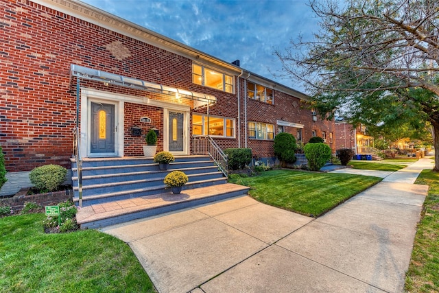 view of property featuring brick siding and a front yard