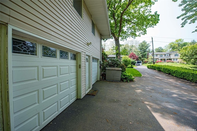 view of side of home featuring a garage and aphalt driveway