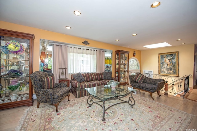 living area with a skylight, wood finished floors, and recessed lighting