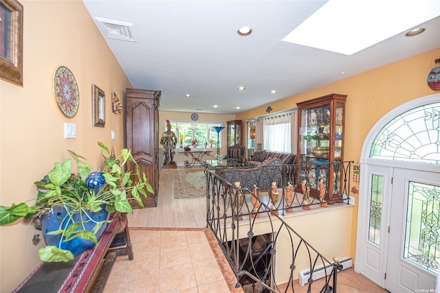 foyer featuring a baseboard radiator, a skylight, recessed lighting, and light tile patterned flooring