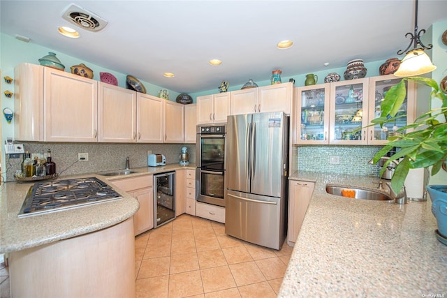 kitchen featuring light brown cabinets, stainless steel appliances, a sink, and visible vents