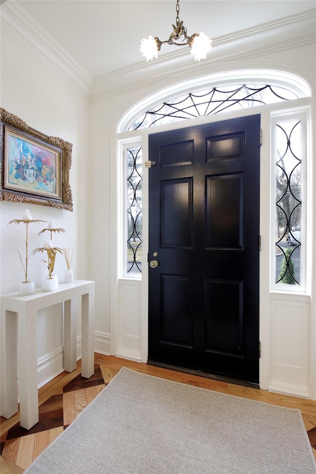 entryway featuring ornamental molding, a notable chandelier, and wood finished floors