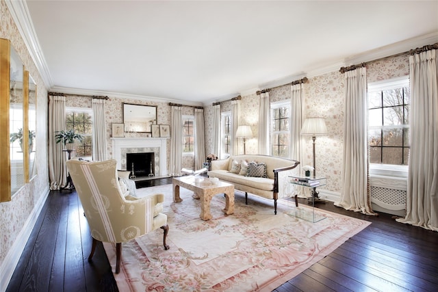 living room with wallpapered walls, baseboards, dark wood-style flooring, crown molding, and a fireplace