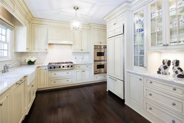 kitchen with decorative backsplash, dark wood-style floors, glass insert cabinets, hanging light fixtures, and stainless steel appliances