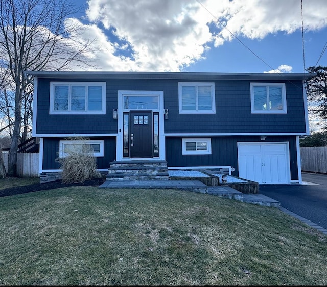 split foyer home with entry steps, aphalt driveway, a front lawn, and a garage