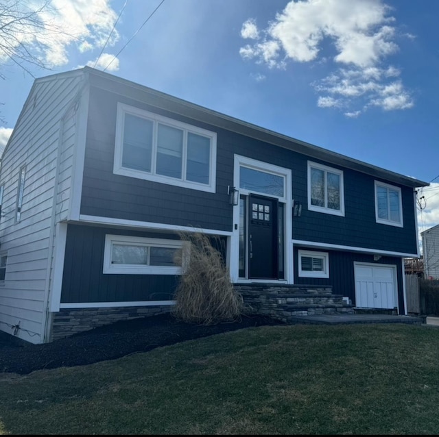 raised ranch with a garage and a front lawn