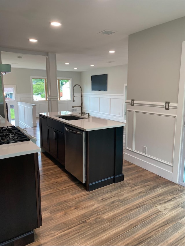 kitchen featuring appliances with stainless steel finishes, light countertops, a sink, and an island with sink