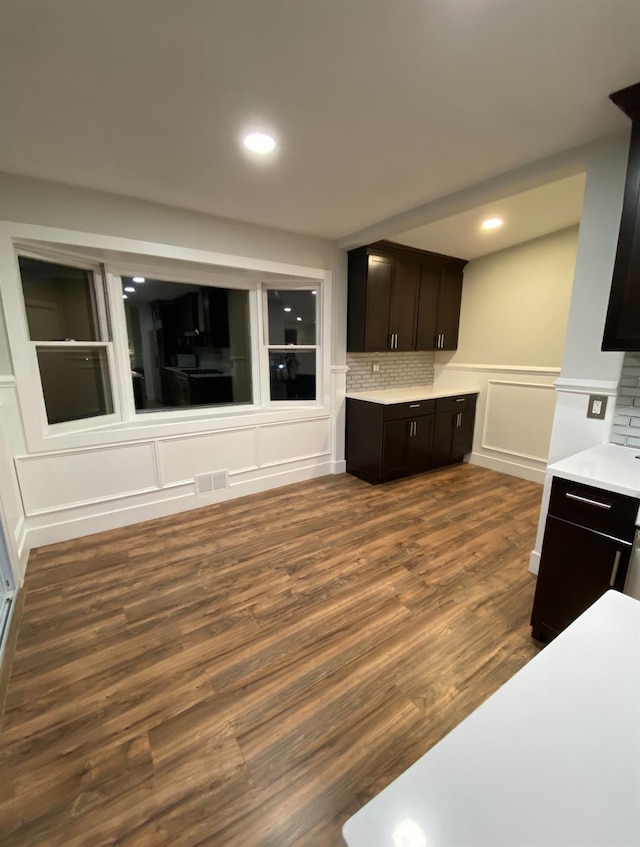 kitchen with light countertops, dark brown cabinetry, visible vents, and a decorative wall