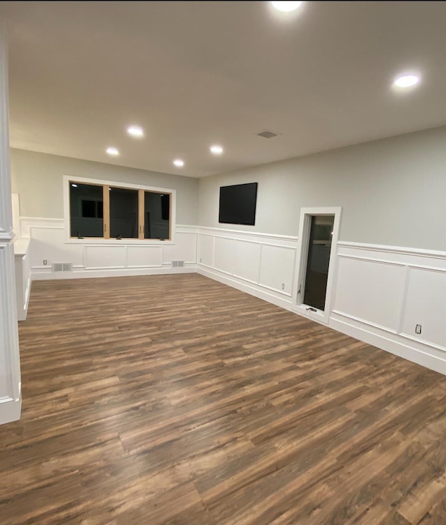 unfurnished living room featuring a wainscoted wall, visible vents, dark wood-style flooring, and recessed lighting