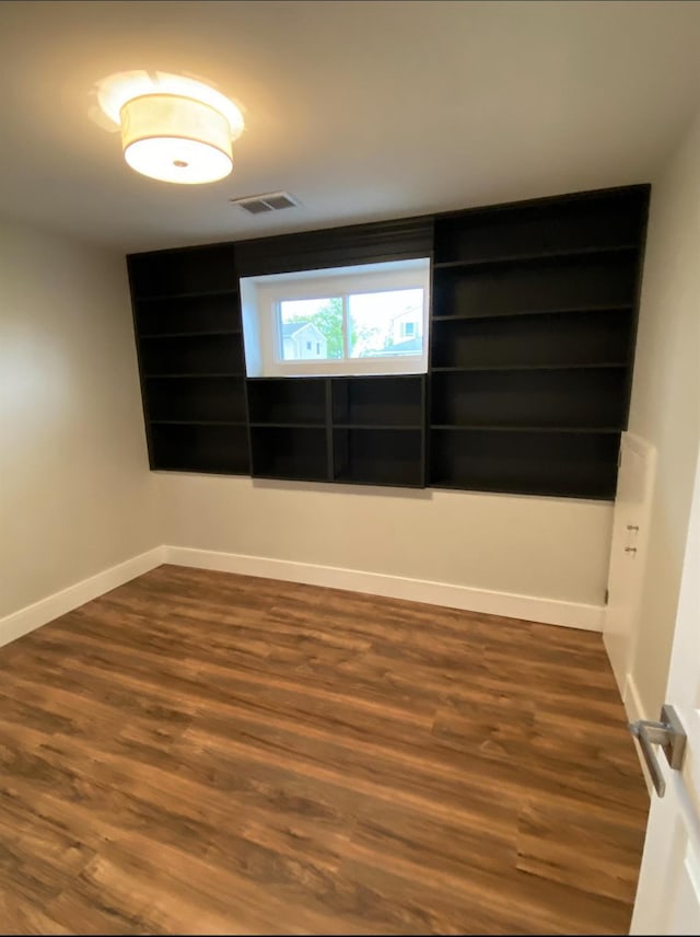 unfurnished room featuring baseboards, visible vents, and dark wood finished floors