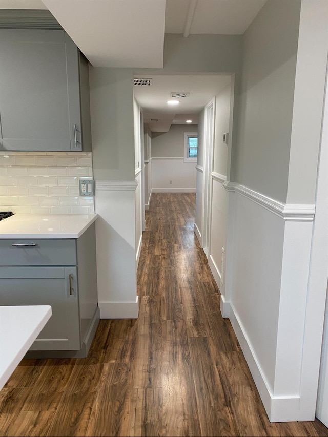 corridor featuring baseboards, visible vents, and dark wood-type flooring