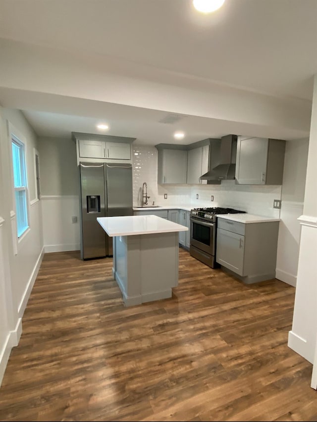 kitchen featuring wall chimney exhaust hood, gray cabinets, appliances with stainless steel finishes, and light countertops