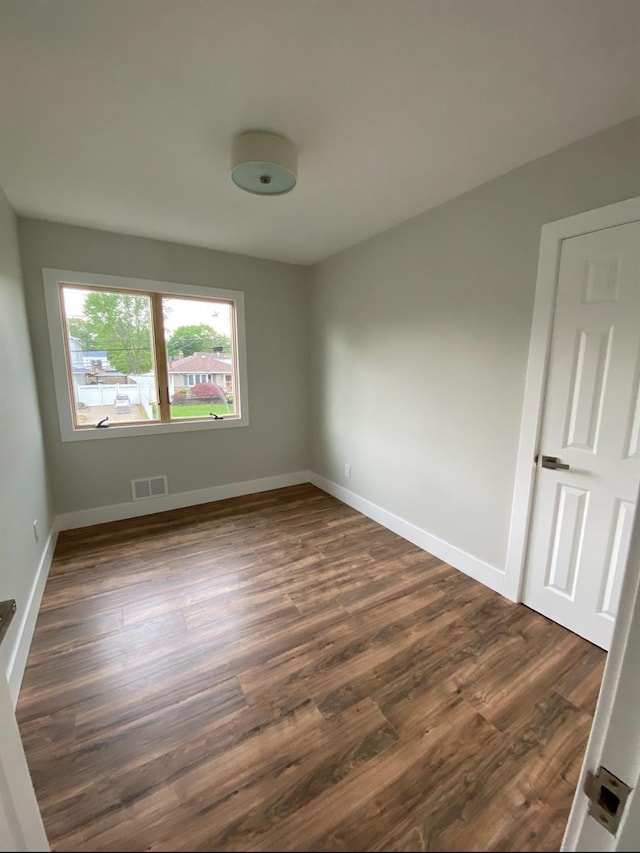 spare room featuring dark wood finished floors, visible vents, and baseboards