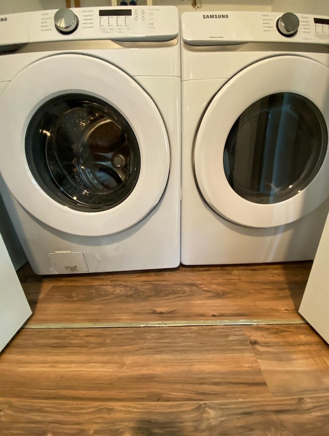 laundry room with laundry area, wood finished floors, and washing machine and clothes dryer