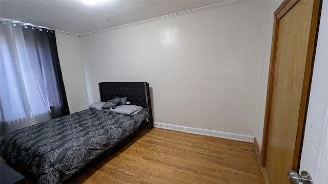 bedroom with light wood-style floors, baseboards, and ornamental molding