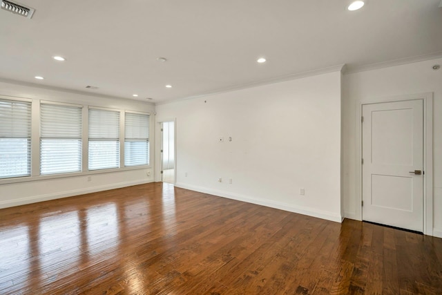 empty room with visible vents, crown molding, baseboards, and wood finished floors