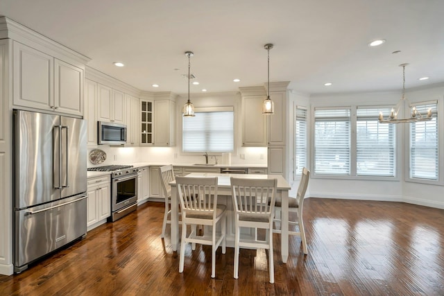 kitchen featuring premium appliances, glass insert cabinets, dark wood-type flooring, light countertops, and a sink