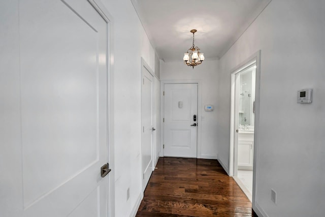 entryway with dark wood-style floors, a chandelier, and baseboards