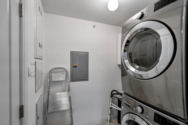 clothes washing area with laundry area, electric panel, baseboards, and stacked washer and clothes dryer