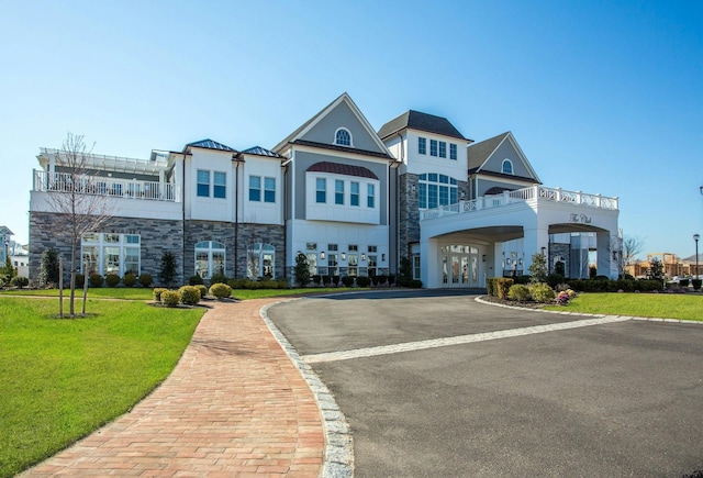 view of front of house with driveway, stone siding, and a front lawn