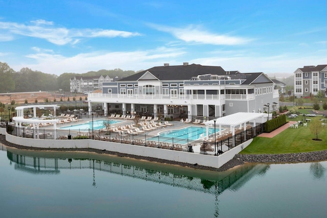 rear view of property featuring a yard, a patio area, a water view, and a community pool