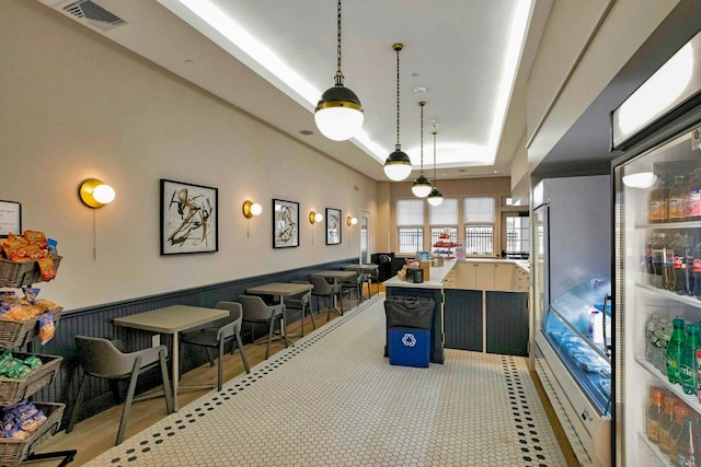 game room featuring a wainscoted wall, visible vents, and a raised ceiling