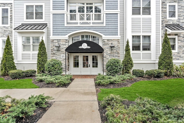 view of exterior entry featuring metal roof, stone siding, french doors, and a standing seam roof